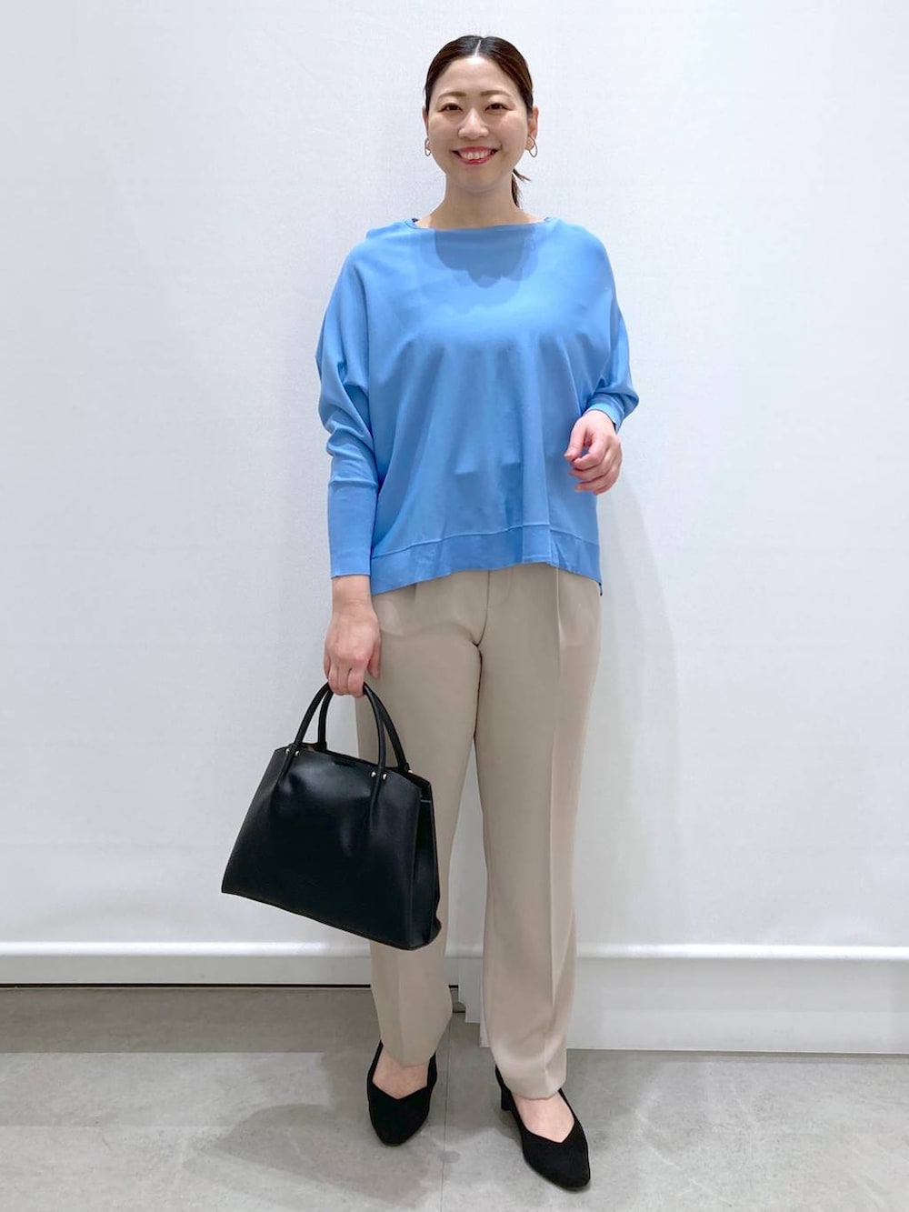 ブラック系のショルダーバッグ、ブルー系のニット/セーター、ベージュ系のその他パンツを着用したレディースの春コーディネートの2枚目の写真