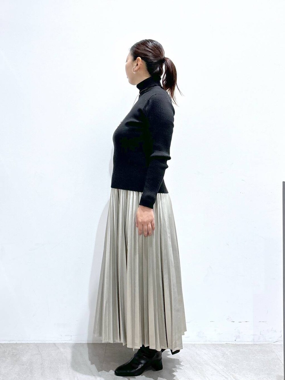 ブラック系のTシャツ/カットソー、ブラック系のブーツ、シルバー系のスカートを着用したレディースの秋コーディネートの3枚目の写真