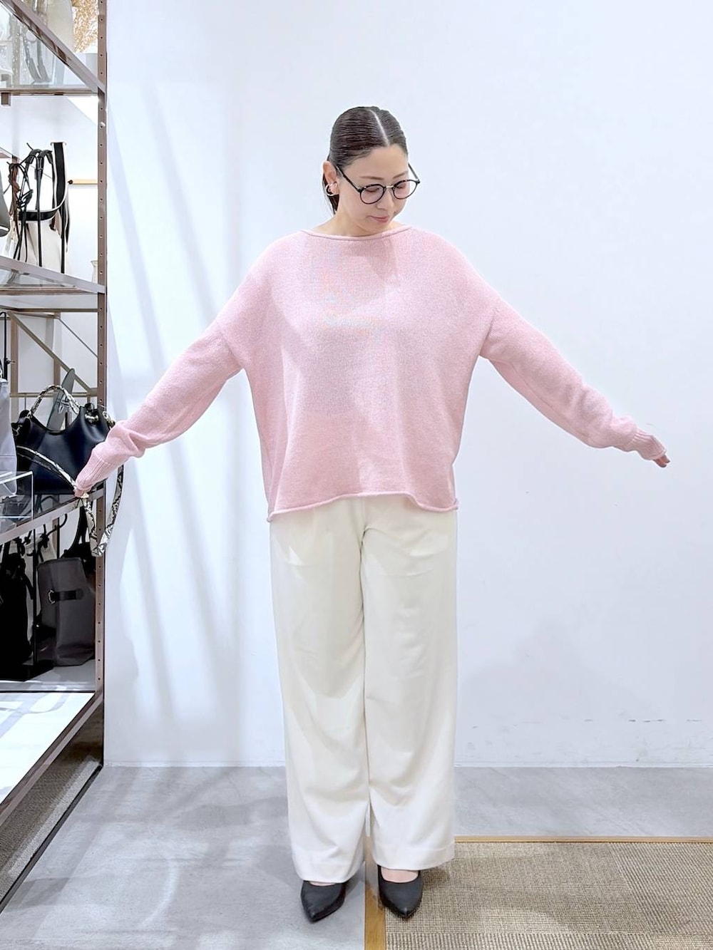 ブラック系のその他パンツ、ピンク系のニット/セーター、ブラック系のハンドバッグを着用したレディースの春コーディネートの6枚目の写真