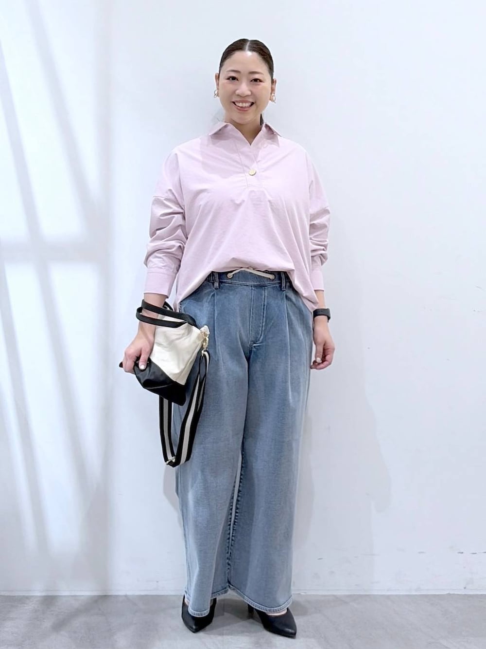 ブルー系のデニムパンツ、ピンク系のシャツ/ブラウス、ベージュ系のショルダーバッグを着用したレディースの春コーディネートの2枚目の写真