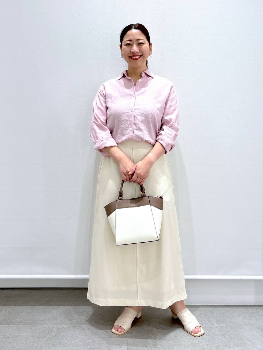 ピンク系のシャツ/ブラウス、ホワイト系のサンダル、ホワイト系のハンドバッグを着用したレディースの春コーディネートの2枚目の写真