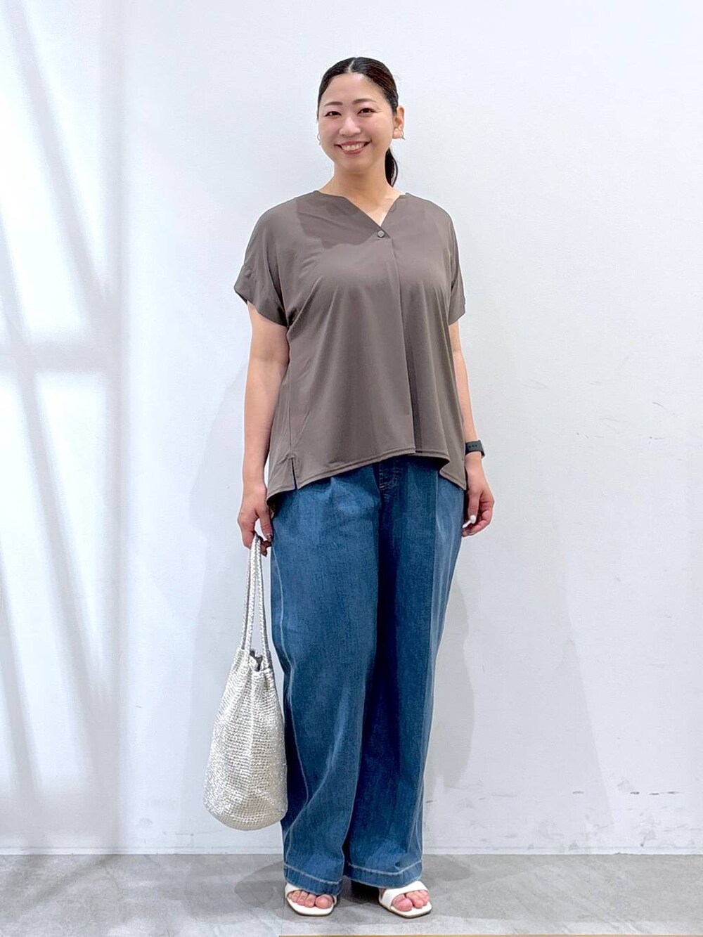 グリーン系のTシャツ/カットソー、シルバー系のトートバッグ、ブルー系のデニムパンツを着用したレディースの夏コーディネートの2枚目の写真