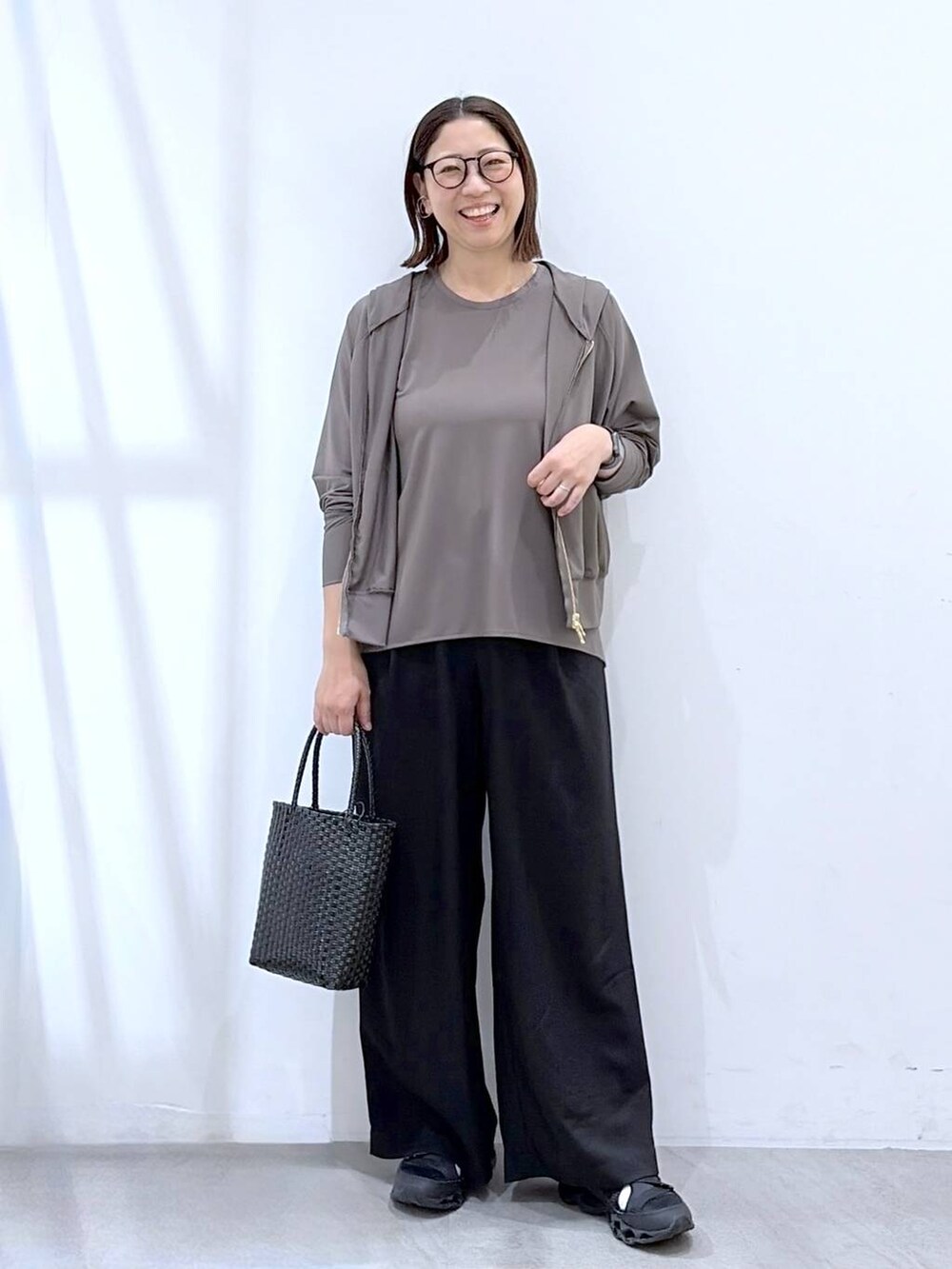 ブラック系のその他パンツ、ブラック系のかごバッグ、グレー系のパーカーを着用したレディースの夏コーディネートの2枚目の写真