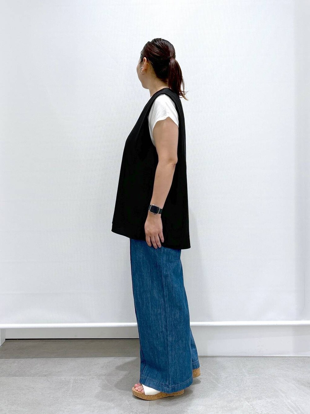 ブルー系のデニムパンツ、ブラック系のシャツ/ブラウス、ホワイト系のサンダルを着用したレディースの夏コーディネートの3枚目の写真