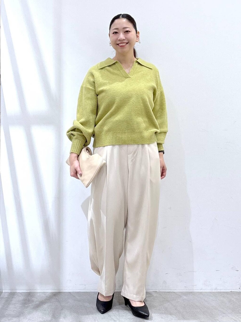 ブラック系のパンプス、ホワイト系のその他パンツ、イエロー系のニット/セーターを着用したレディースの冬コーディネートの2枚目の写真