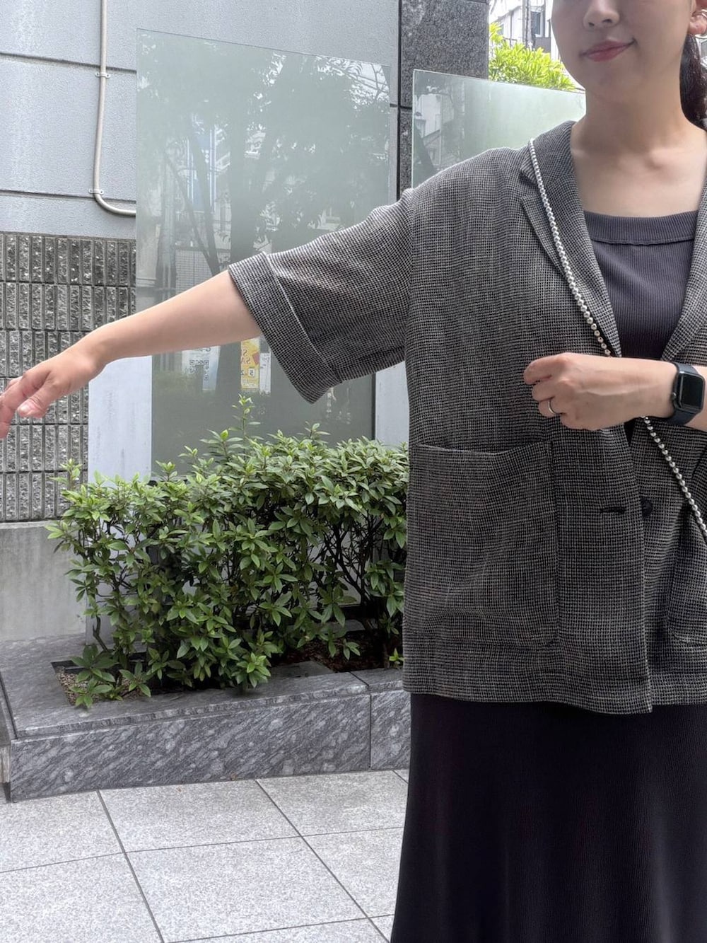ブラック系のテーラードジャケット、グレー系のワンピース、その他のスマホグッズを着用したレディースの夏コーディネートの3枚目の写真