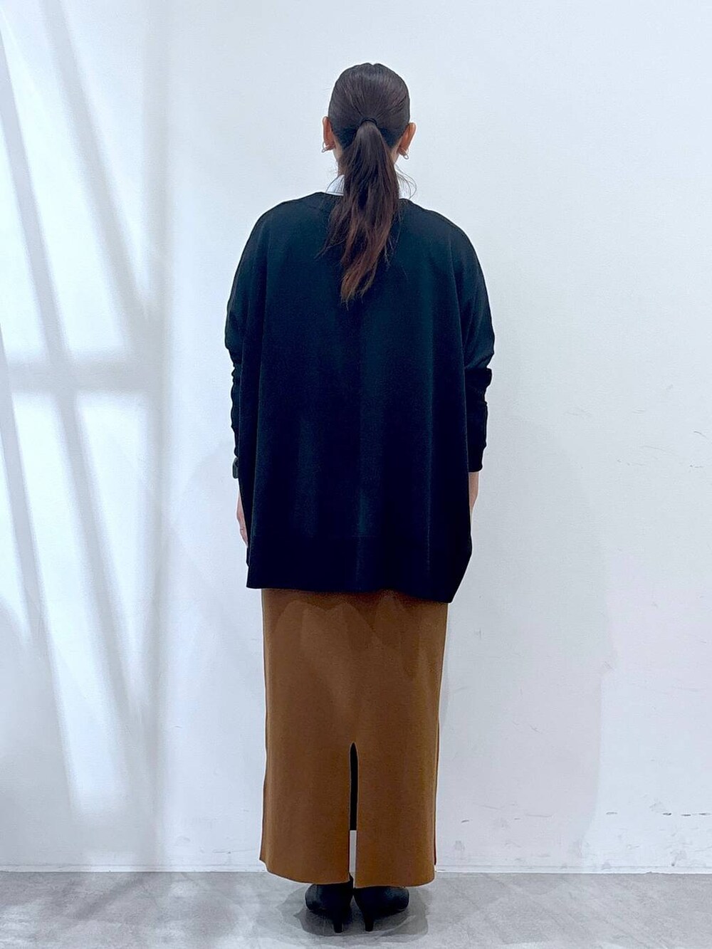 ブラック系のパンプス、ブラック系のカーディガン/ボレロ、イエロー系のスカートを着用したレディースの秋コーディネートの4枚目の写真