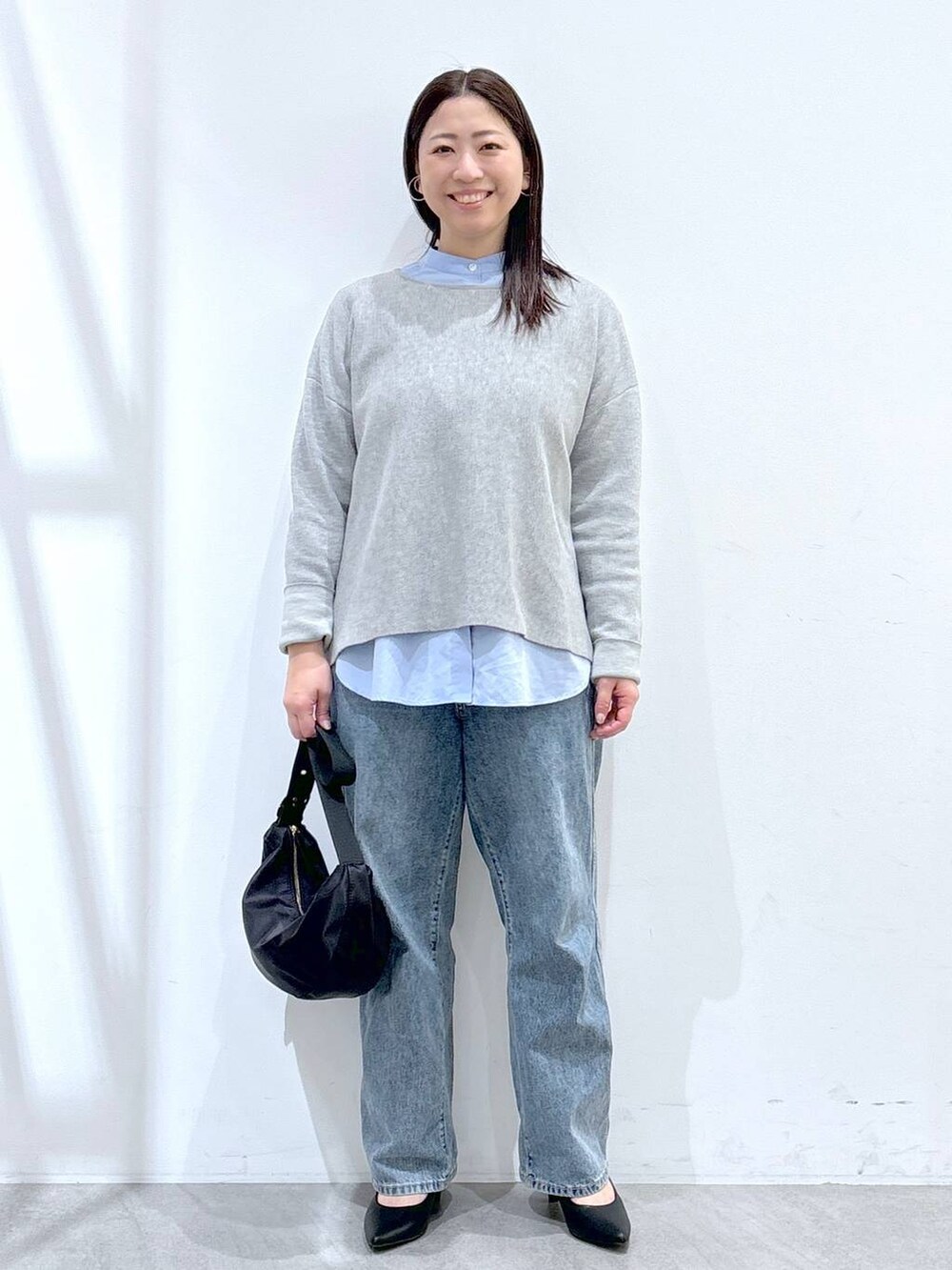 ブルー系のデニムパンツ、ブラック系のハンドバッグ、グレー系のニット/セーターを着用したレディースの冬コーディネートの2枚目の写真