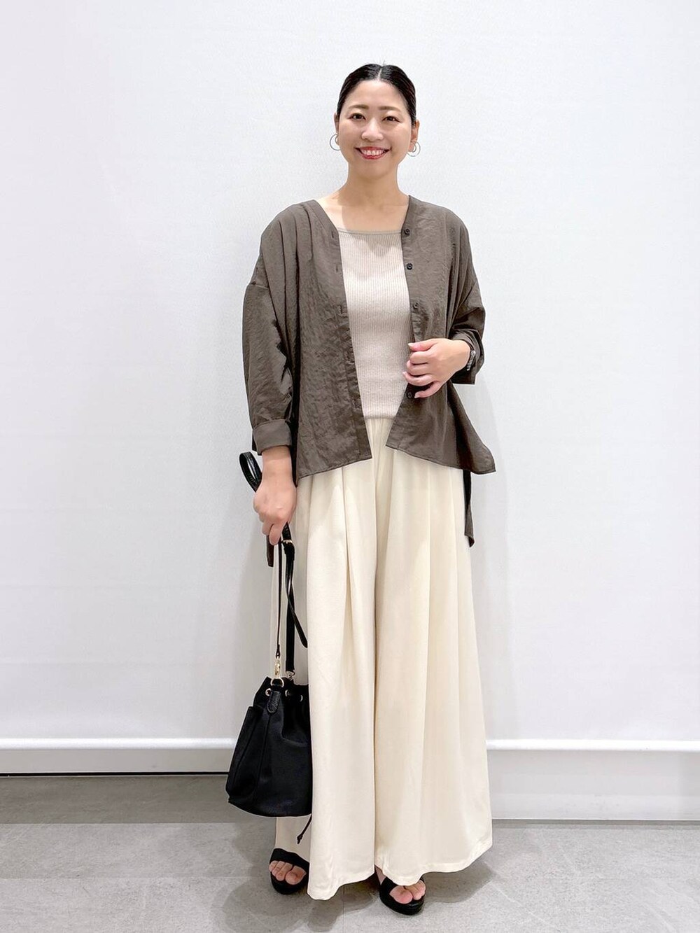 ブラウン系のシャツ/ブラウス、ホワイト系のその他パンツ、ブラック系のハンドバッグを着用したレディースの夏コーディネートの2枚目の写真