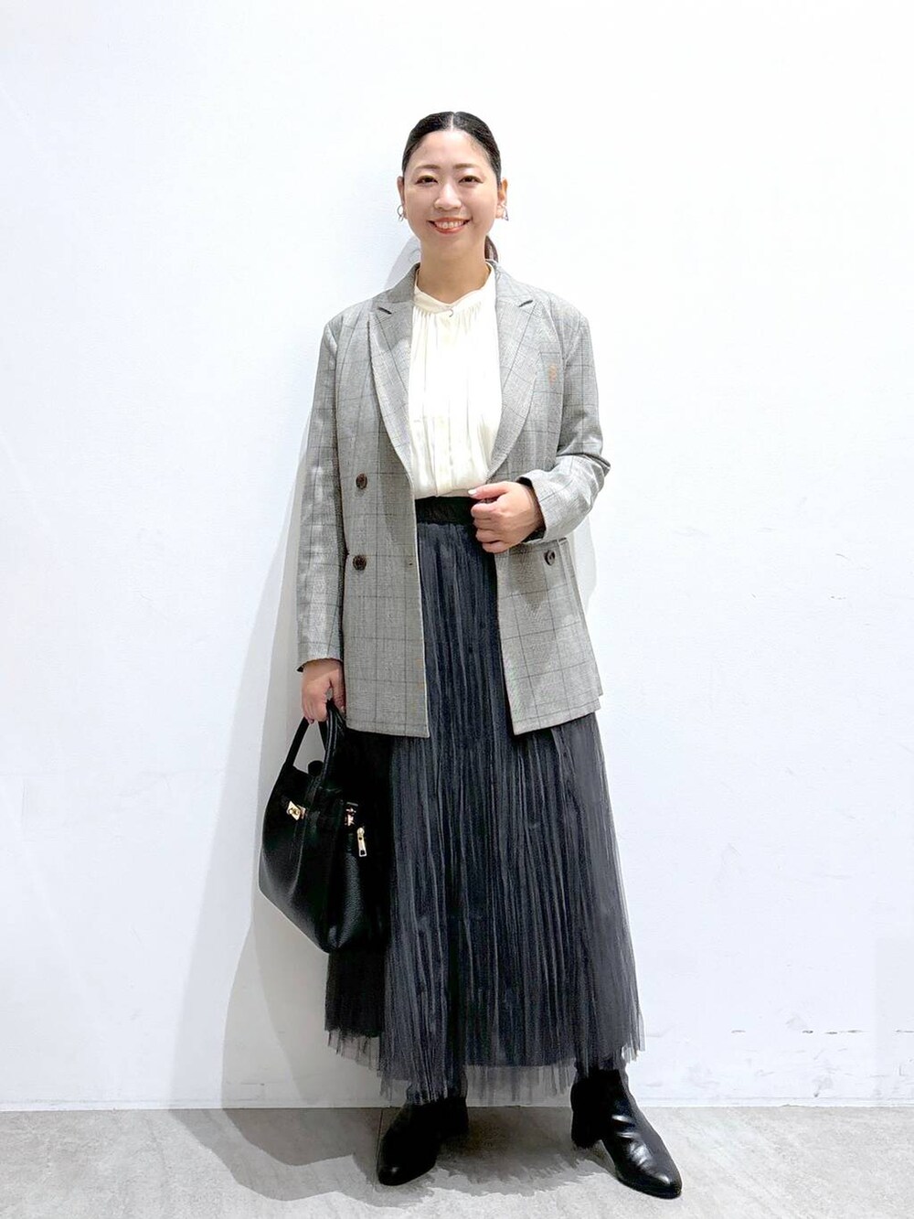 ブラック系のその他アウター、ブラック系のハンドバッグ、グレー系のスカートを着用したレディースの秋コーディネートの2枚目の写真