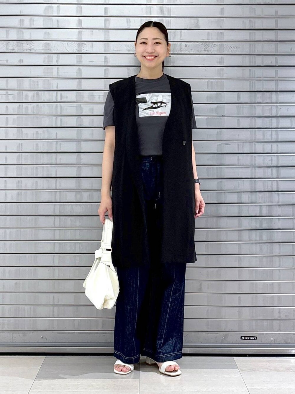 グレー系のTシャツ/カットソー、ブルー系のデニムパンツ、ホワイト系のハンドバッグを着用したレディースの春コーディネートの2枚目の写真