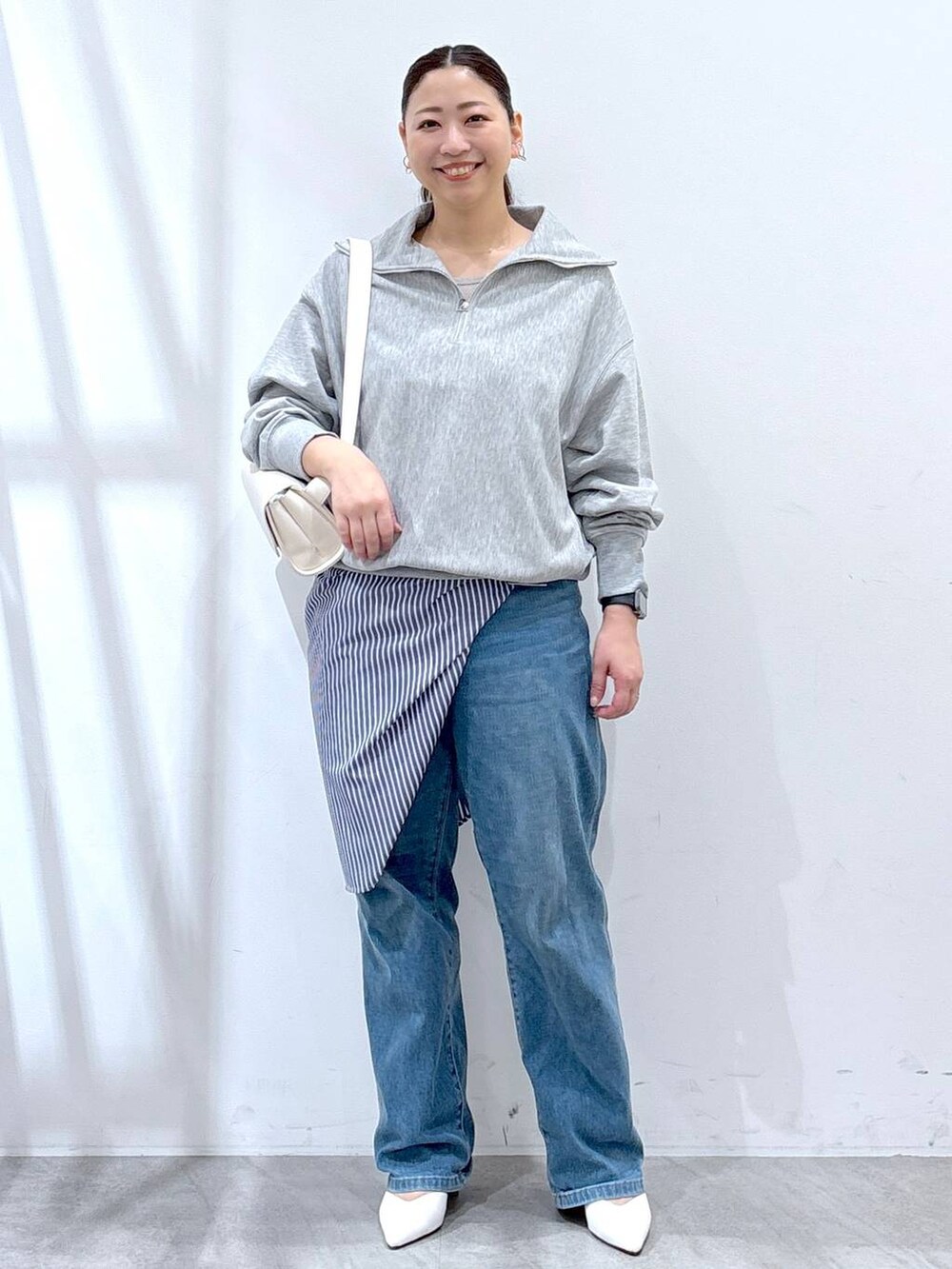 ホワイト系のハンドバッグ、ブルー系のデニムパンツ、グレー系のTシャツ/カットソーを着用したレディースの春コーディネートの2枚目の写真