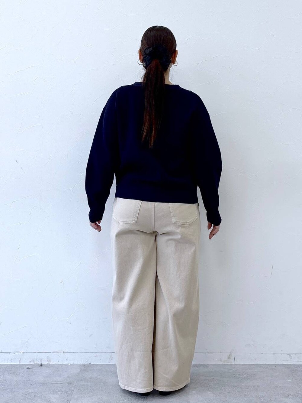 ブラック系のハンドバッグ、ベージュ系のデニムパンツ、ブラック系のパンプスを着用したレディースの冬コーディネートの4枚目の写真