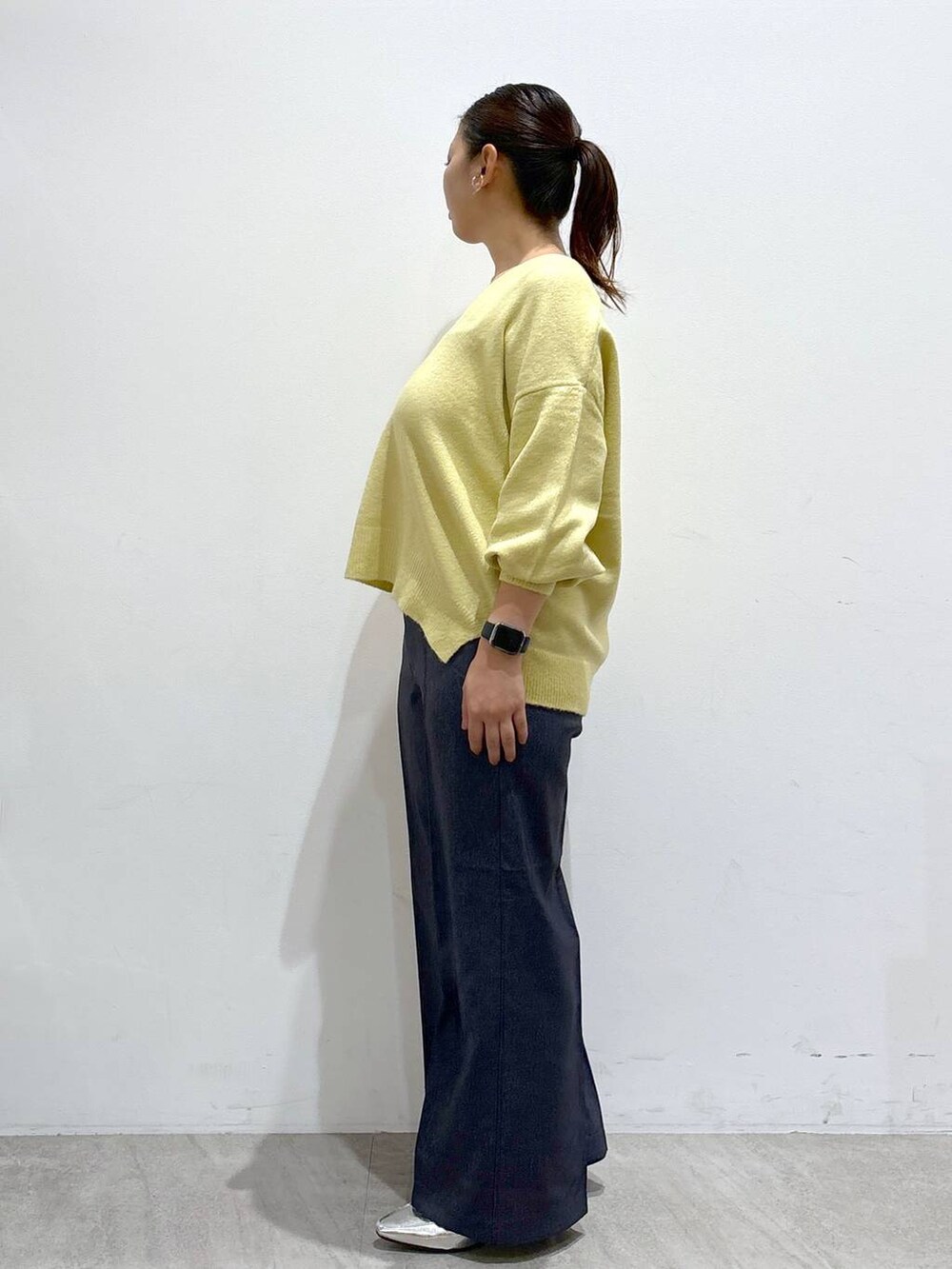 シルバー系のローファー、イエロー系のニット/セーター、ブルー系のデニムパンツを着用したレディースの秋コーディネートの3枚目の写真