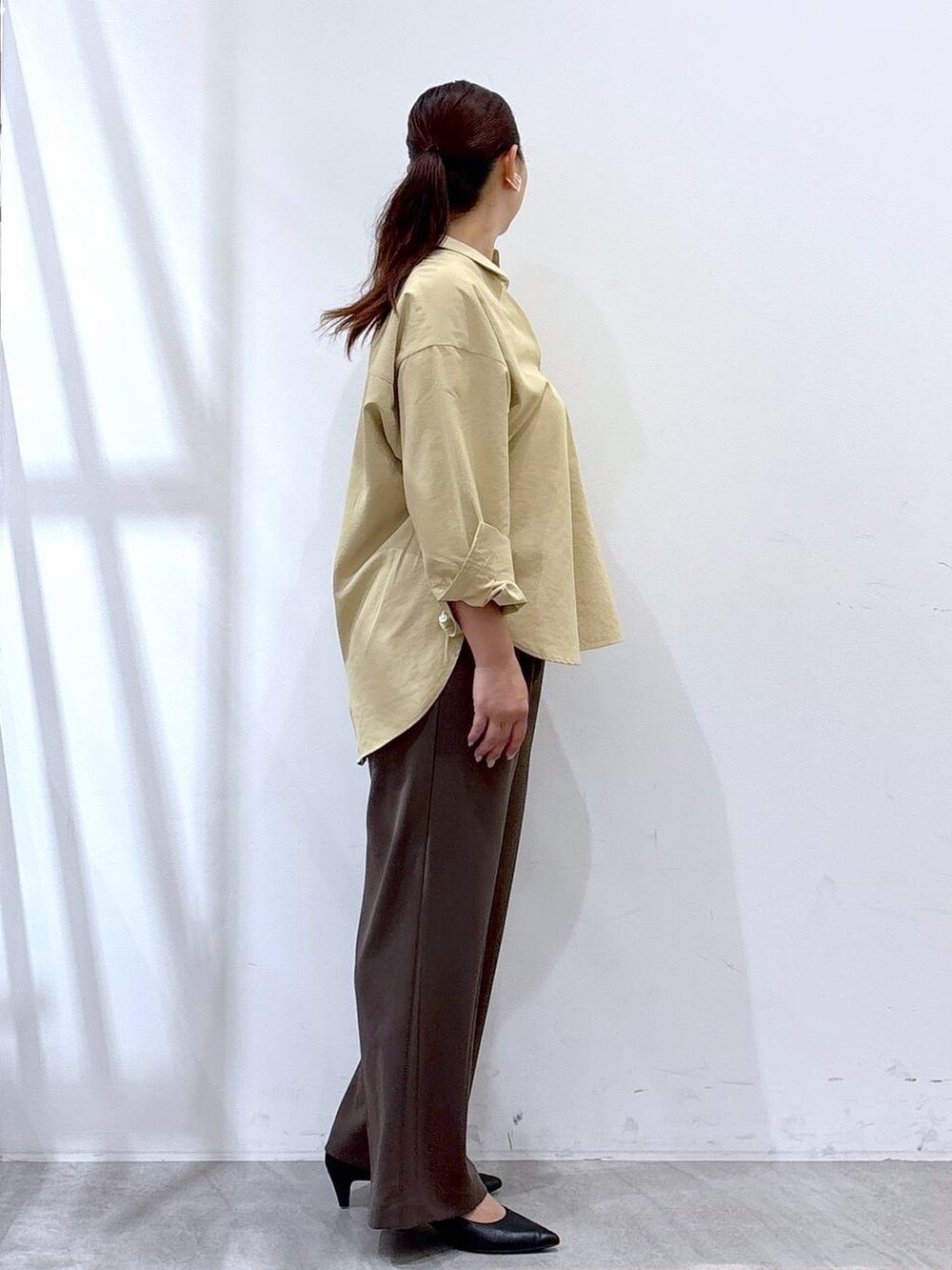 ブラック系のパンプス、イエロー系のシャツ/ブラウス、ブラック系のハンドバッグを着用したレディースの秋コーディネートの5枚目の写真