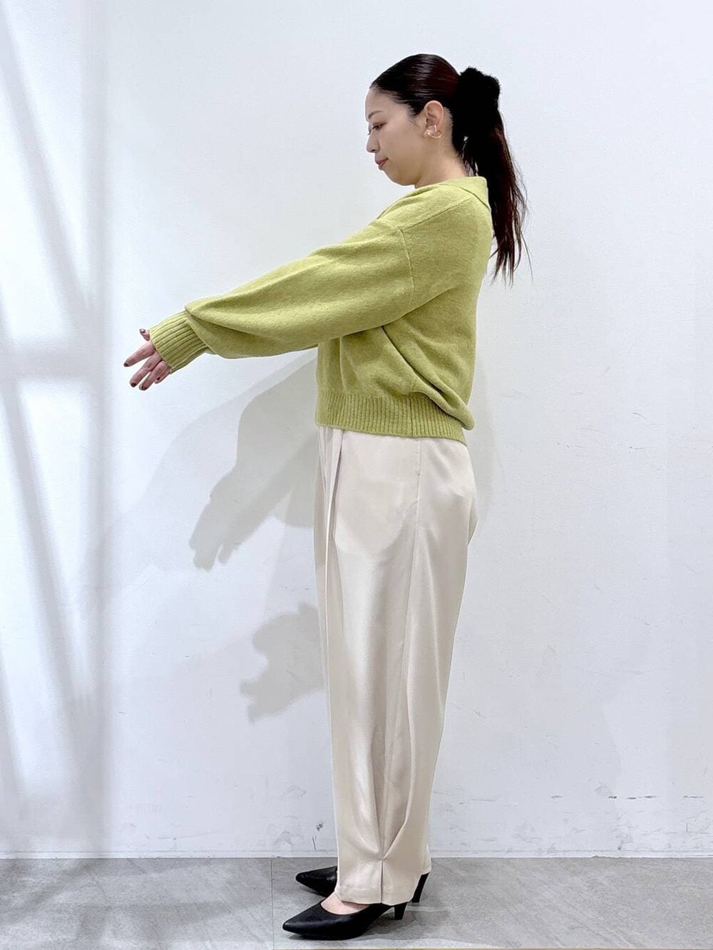 ブラック系のパンプス、ホワイト系のその他パンツ、イエロー系のニット/セーターを着用したレディースの冬コーディネートの4枚目の写真