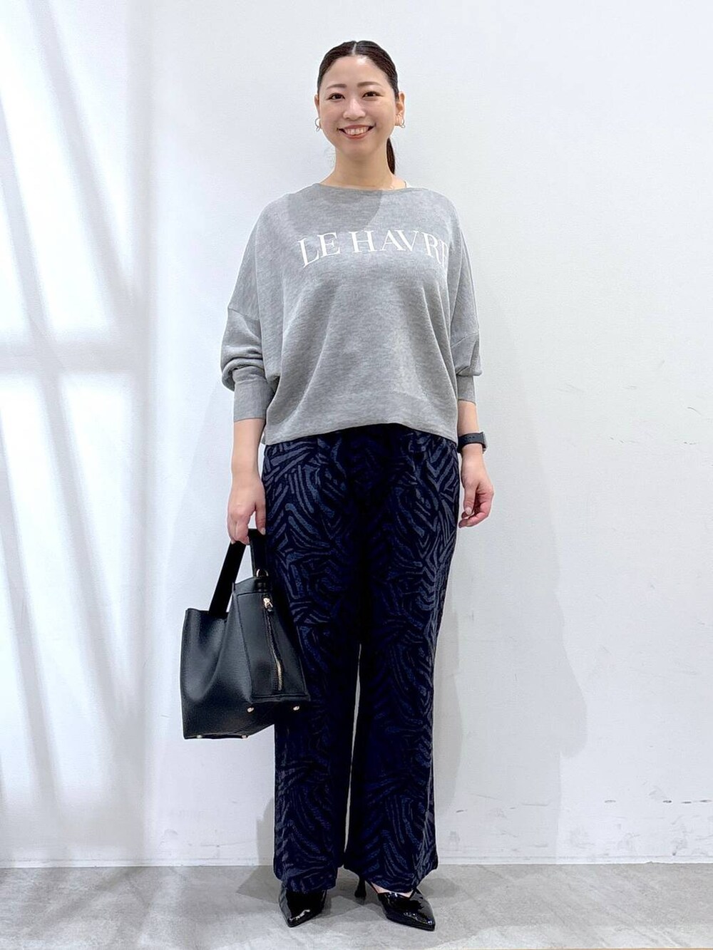 グレー系のニット/セーター、ブルー系のその他パンツ、ブラック系のハンドバッグを着用したレディースの春コーディネートの2枚目の写真