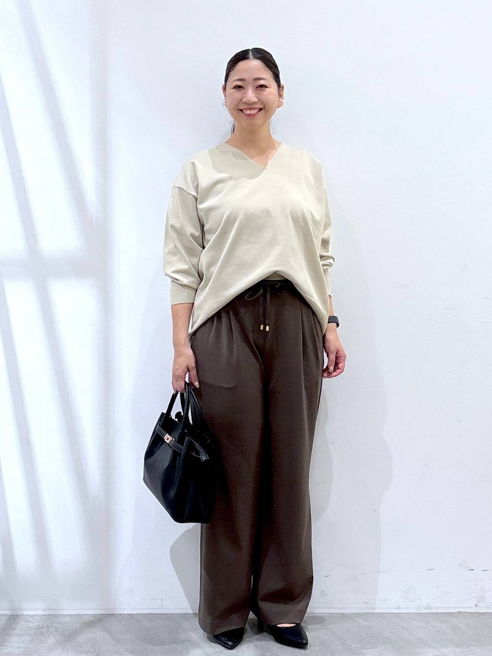 ブラック系のパンプス、ブラック系のハンドバッグ、ブラウン系のその他パンツを着用したレディースの秋コーディネートの2枚目の写真