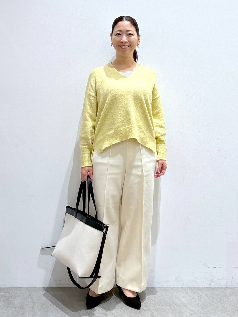 ブラック系のトートバッグ、イエロー系のニット/セーター、ホワイト系のその他パンツを着用したレディースの冬コーディネートの2枚目の写真