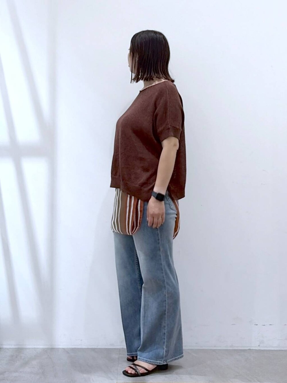 ブラック系のサンダル、ブルー系のデニムパンツ、ブラウン系のストール/ショールを着用したレディースの秋コーディネートの3枚目の写真