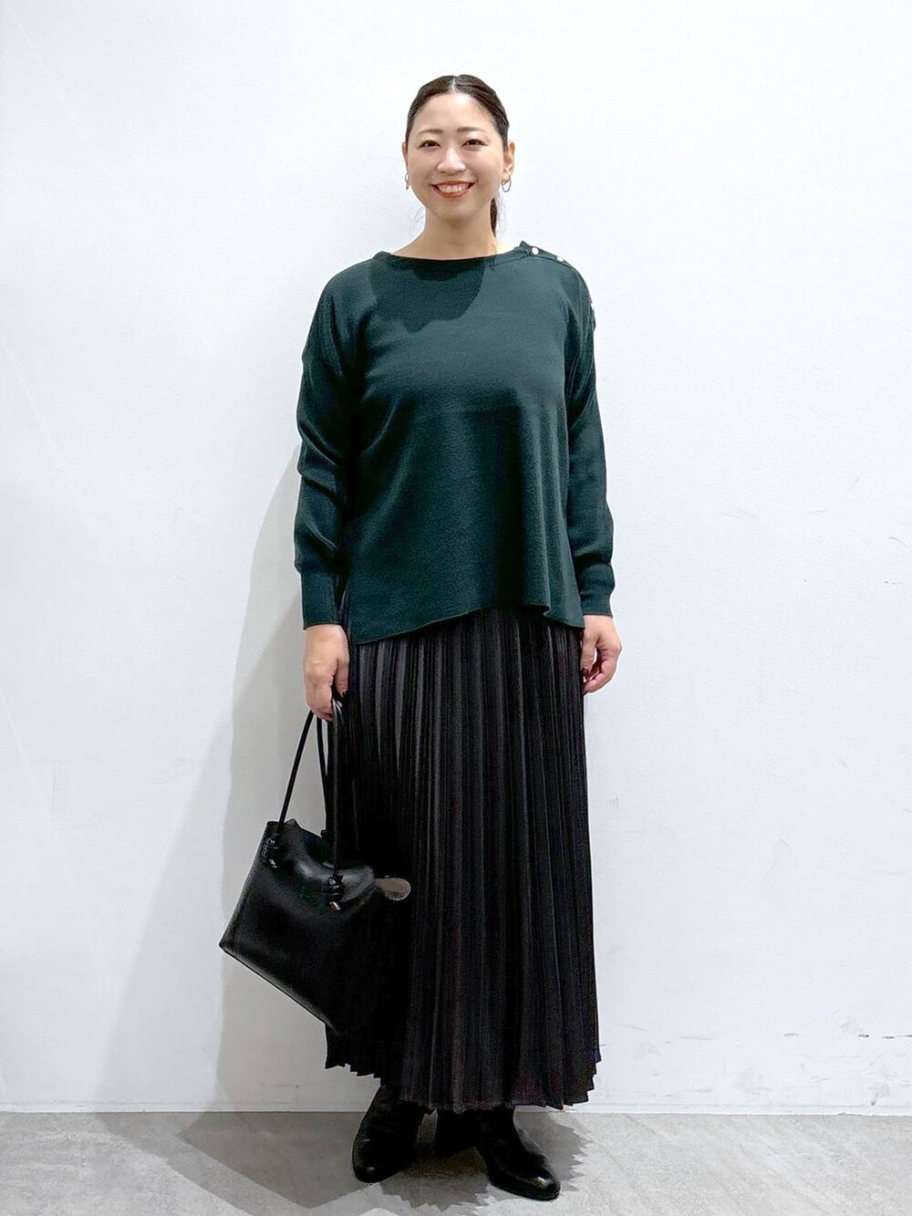 ブラック系のブーツ、グリーン系のニット/セーター、グレー系のスカートを着用したレディースの秋コーディネートの2枚目の写真