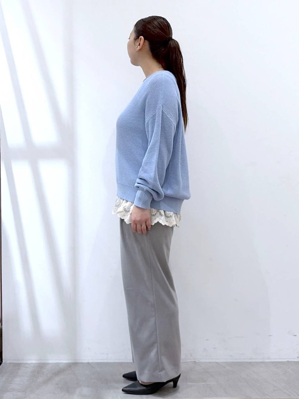 ブルー系のニット/セーター、ホワイト系のタンクトップ、ブラック系のハンドバッグを着用したレディースの春コーディネートの3枚目の写真