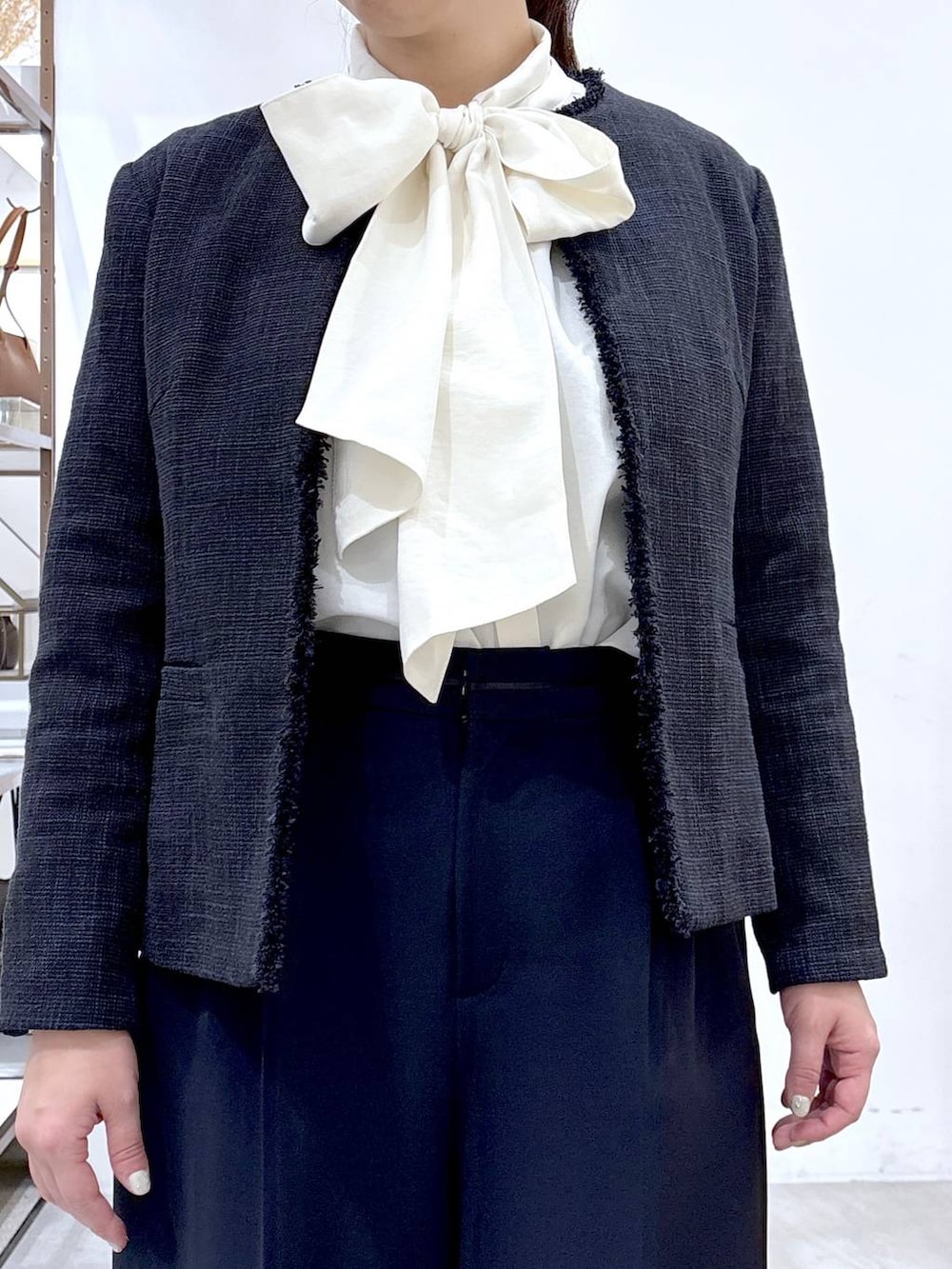 ブラック系のハンドバッグ、ブルー系のノーカラージャケット、ブルー系のスラックスを着用したレディースの冬コーディネートの6枚目の写真