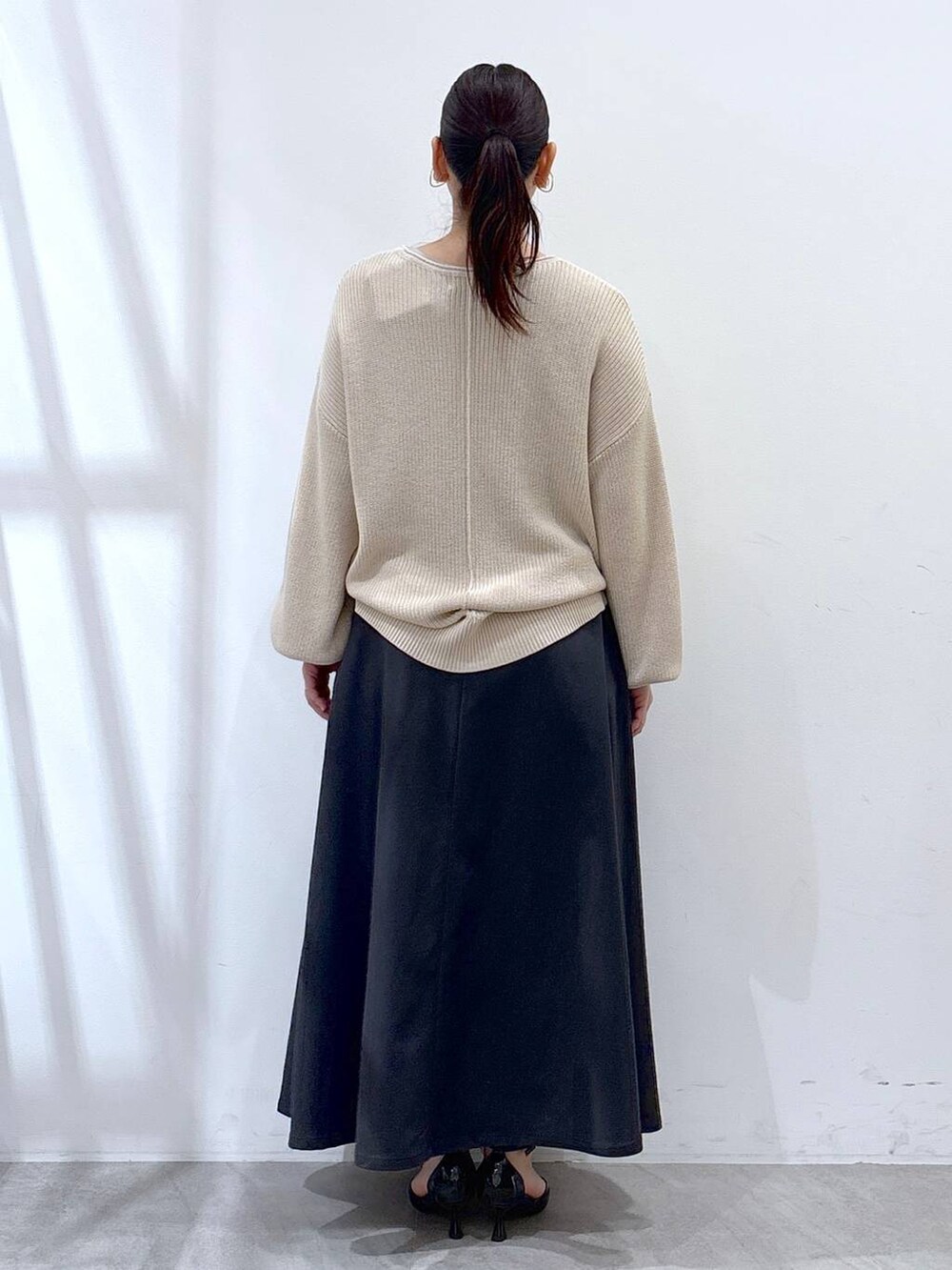 ホワイト系のニット/セーター、グレー系のスカートを着用したレディースの春コーディネートの4枚目の写真