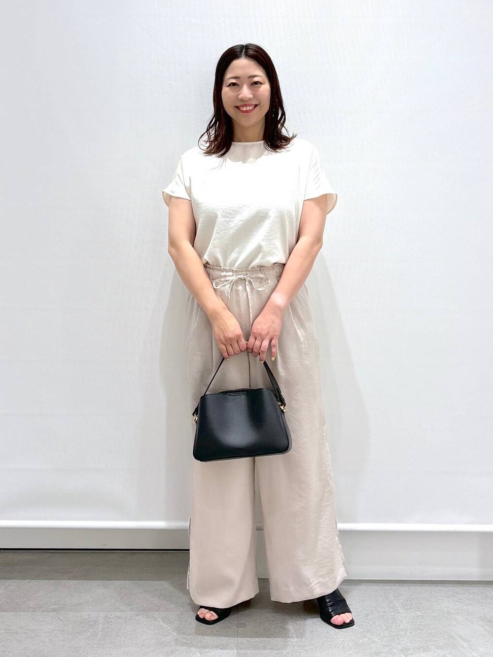 ブラック系のサンダル、ブラック系のハンドバッグ、ベージュ系のその他パンツを着用したレディースの夏コーディネートの2枚目の写真