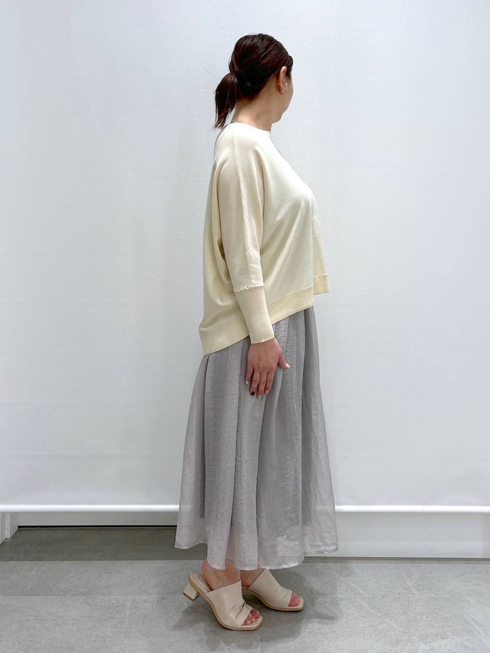 グレー系のスカート、ホワイト系のニット/セーター、ホワイト系のショルダーバッグを着用したレディースの春コーディネートの4枚目の写真