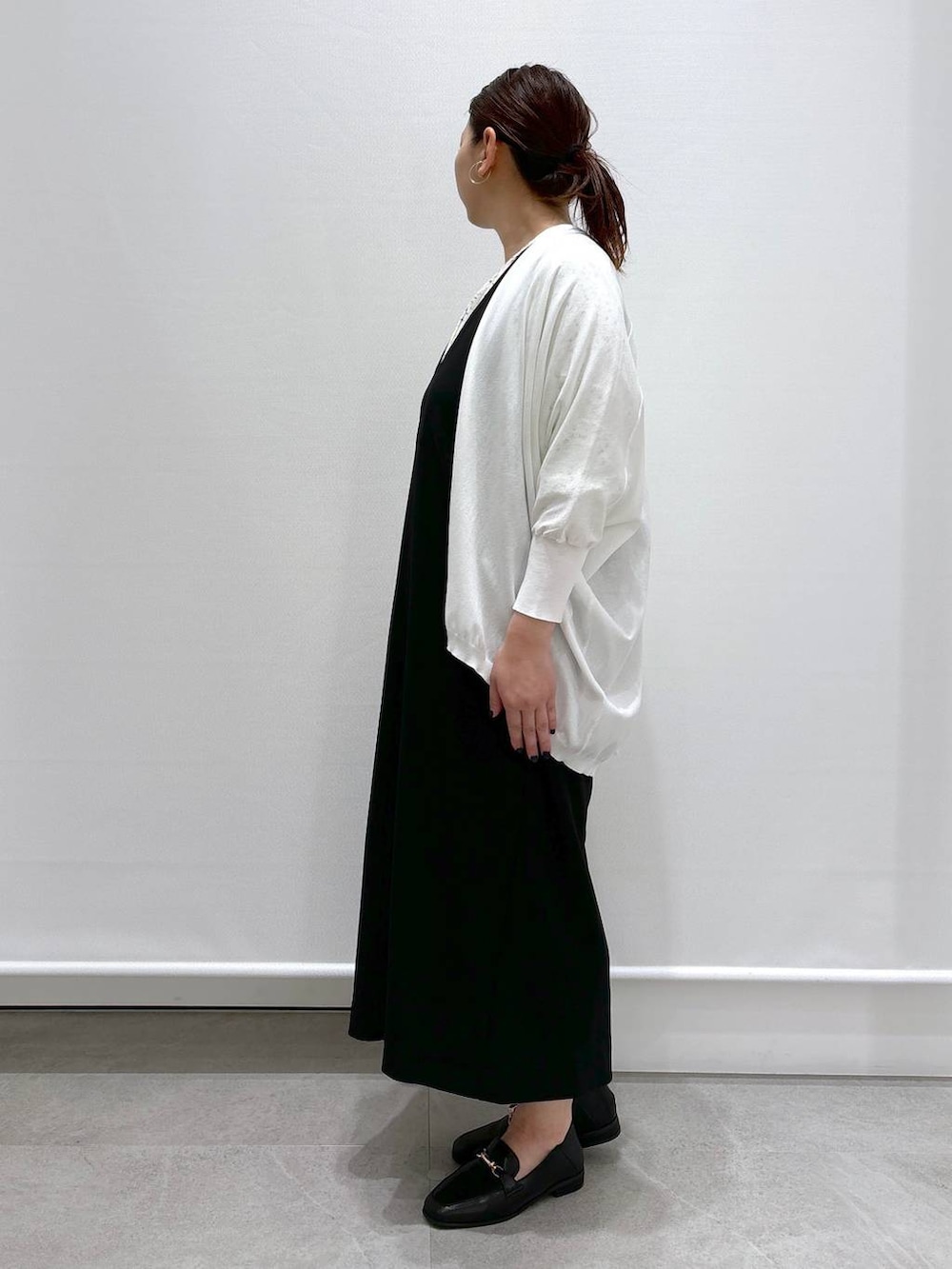 イエロー系のシャツ/ブラウス、ホワイト系のカーディガン/ボレロ、ブラック系のジャンパースカートを着用したレディースの春コーディネートの3枚目の写真