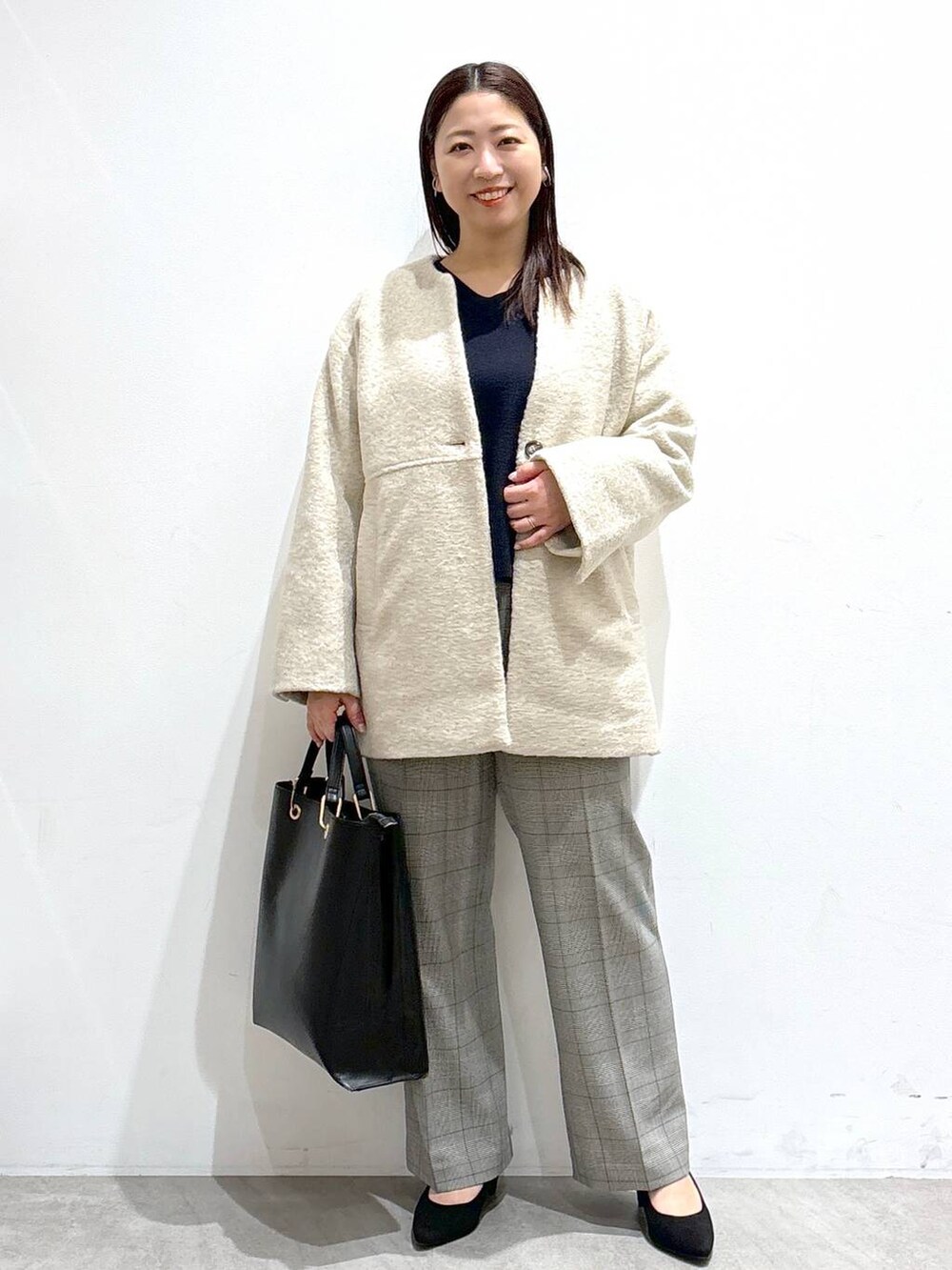 ブラック系のトートバッグ、ベージュ系のその他アウター、ブルー系のニット/セーターを着用したレディースの冬コーディネートの2枚目の写真