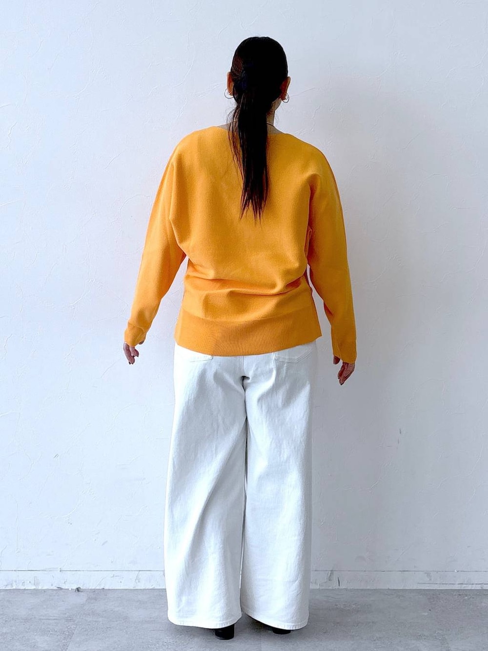 ホワイト系のデニムパンツ、ブラック系のパンプス、ブラック系のトートバッグを着用したレディースの春コーディネートの4枚目の写真