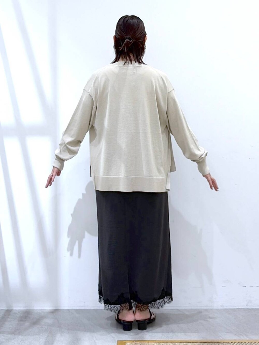 ベージュ系のカーディガン/ボレロ、グレー系のワンピース、ブラック系のサンダルを着用したレディースの秋コーディネートの4枚目の写真