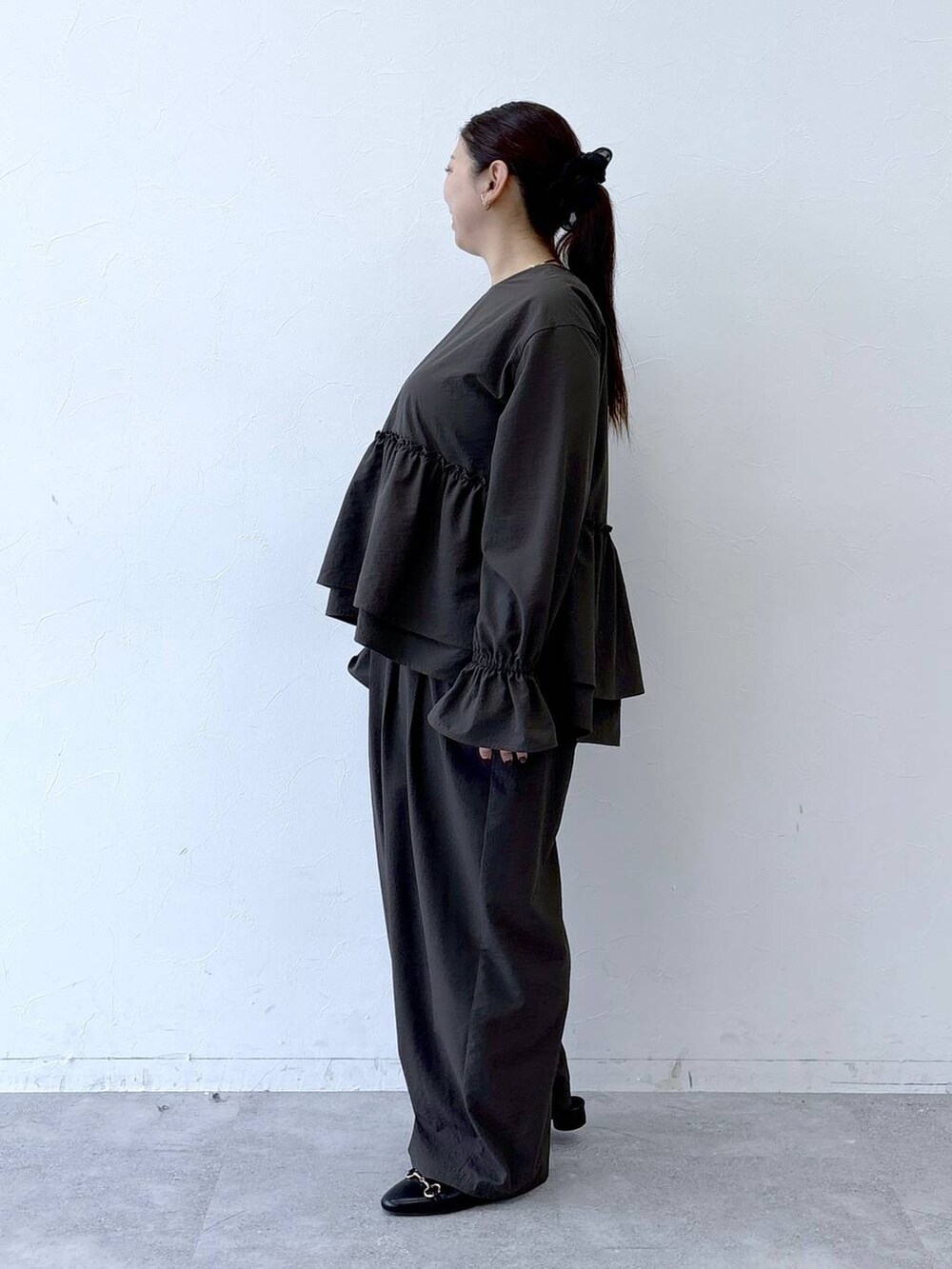 ブラック系のハンドバッグ、ブラック系のパンプス、ブラウン系のその他パンツを着用したレディースの冬コーディネートの3枚目の写真