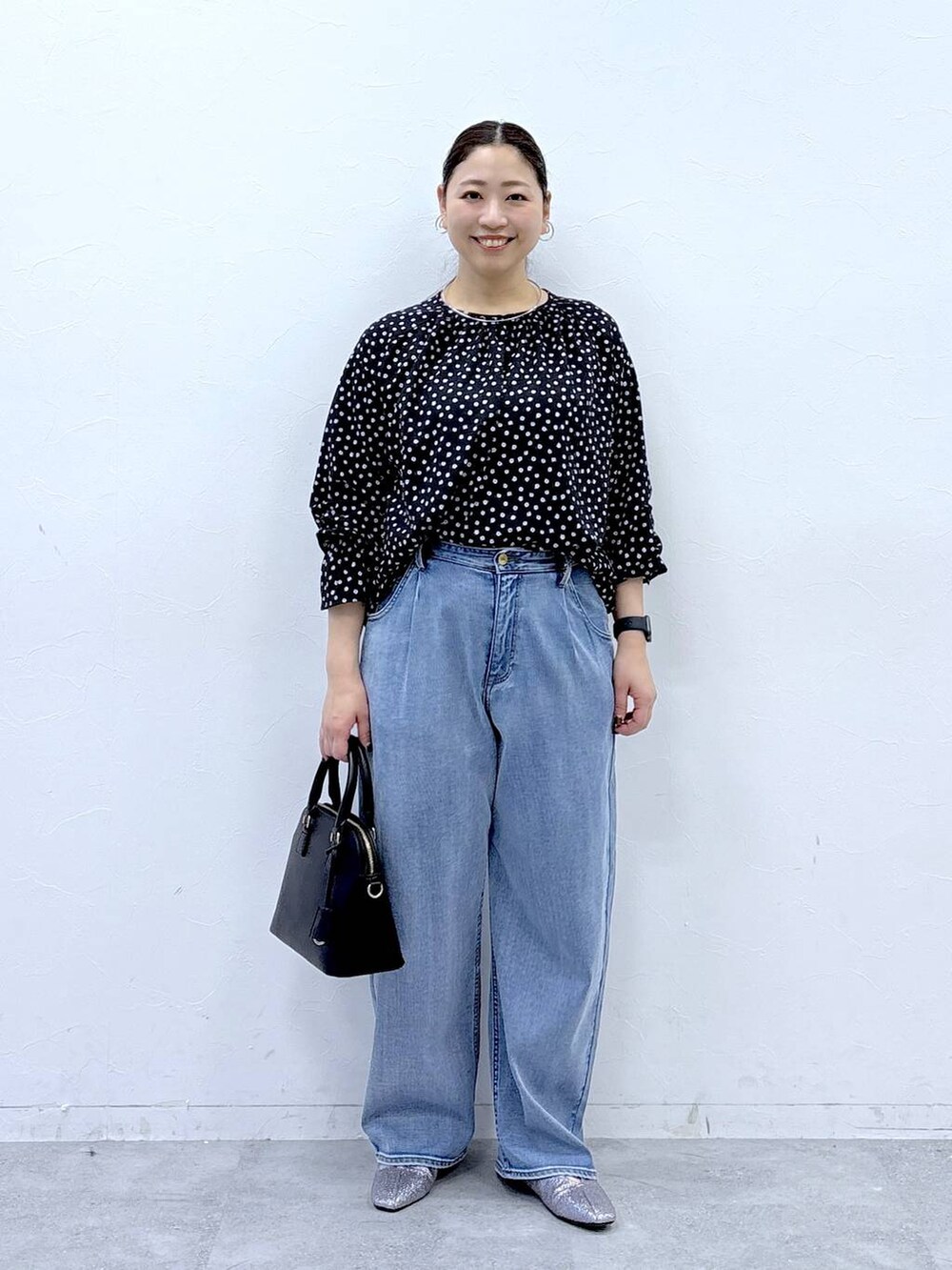 ブラック系のハンドバッグ、ブルー系のデニムパンツ、ブラック系のシャツ/ブラウスを着用したレディースの春コーディネートの2枚目の写真