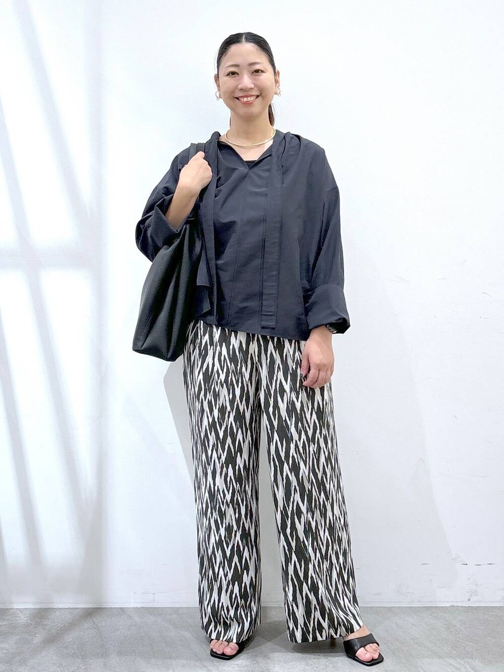 ブルー系のシャツ/ブラウス、ブラック系のトートバッグ、ブラック系のその他パンツを着用したレディースの秋コーディネートの2枚目の写真