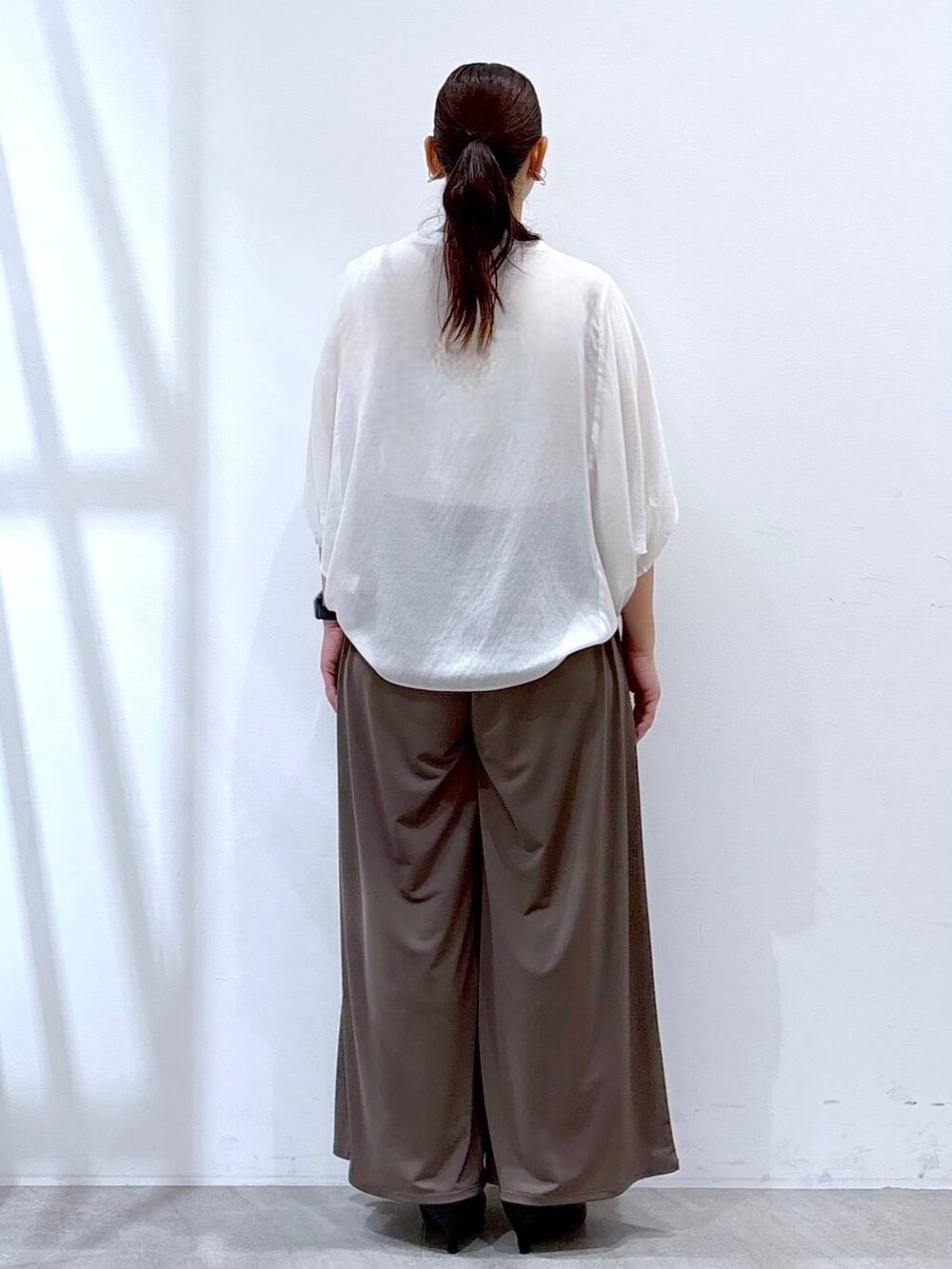 ブラック系のパンプス、ホワイト系のTシャツ/カットソー、ブラック系のハンドバッグを着用したレディースの夏コーディネートの4枚目の写真