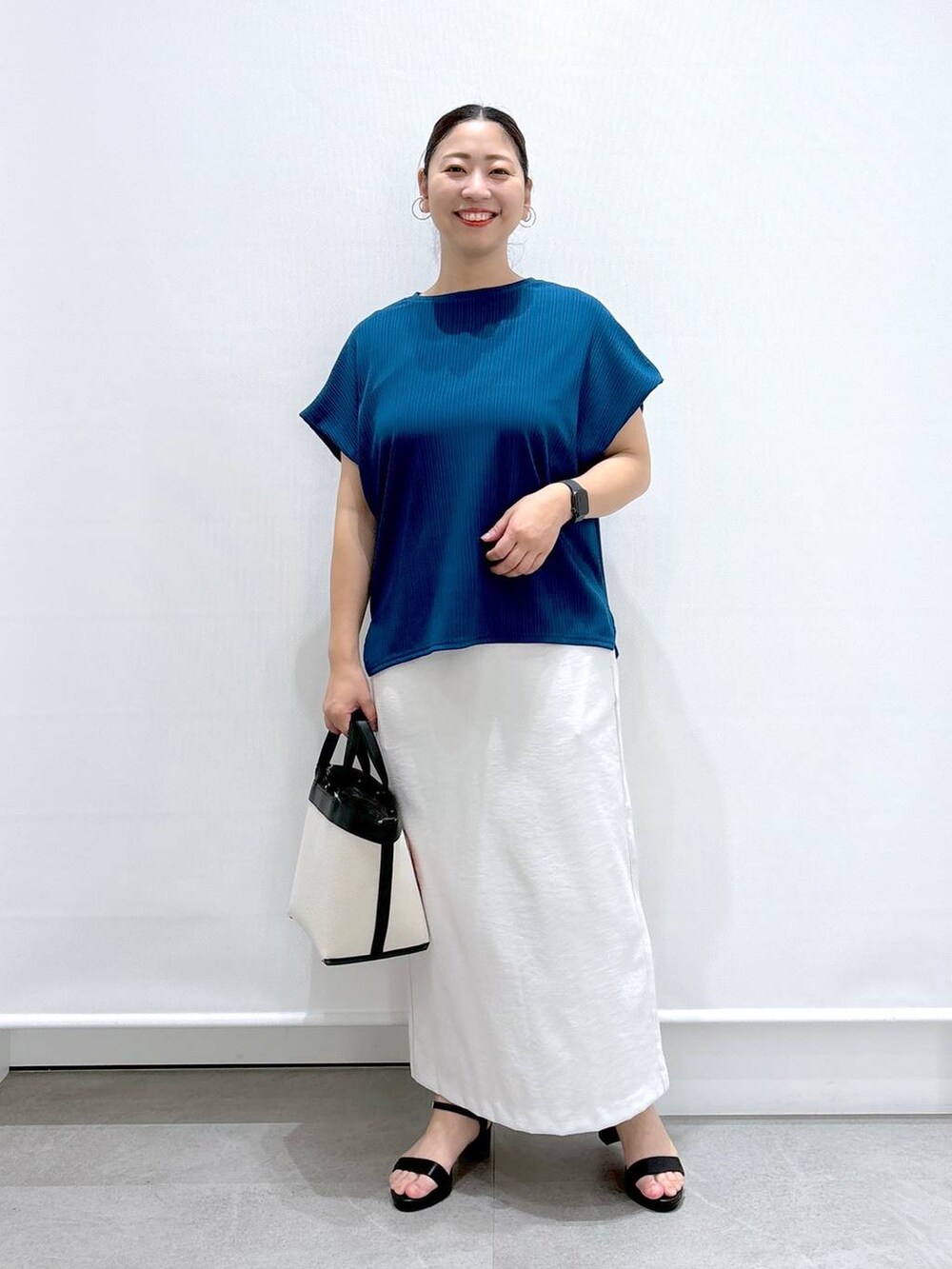 ブルー系のTシャツ/カットソー、グレー系のスカート、ブラック系のトートバッグを着用したレディースの夏コーディネートの2枚目の写真