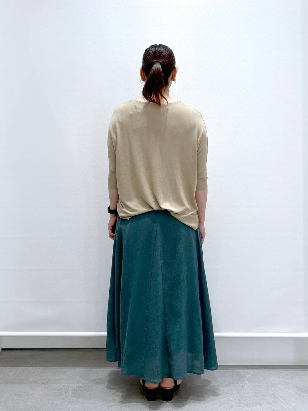 ブラック系のトートバッグ、ブラック系のサンダル、グリーン系のスカートを着用したレディースの夏コーディネートの4枚目の写真