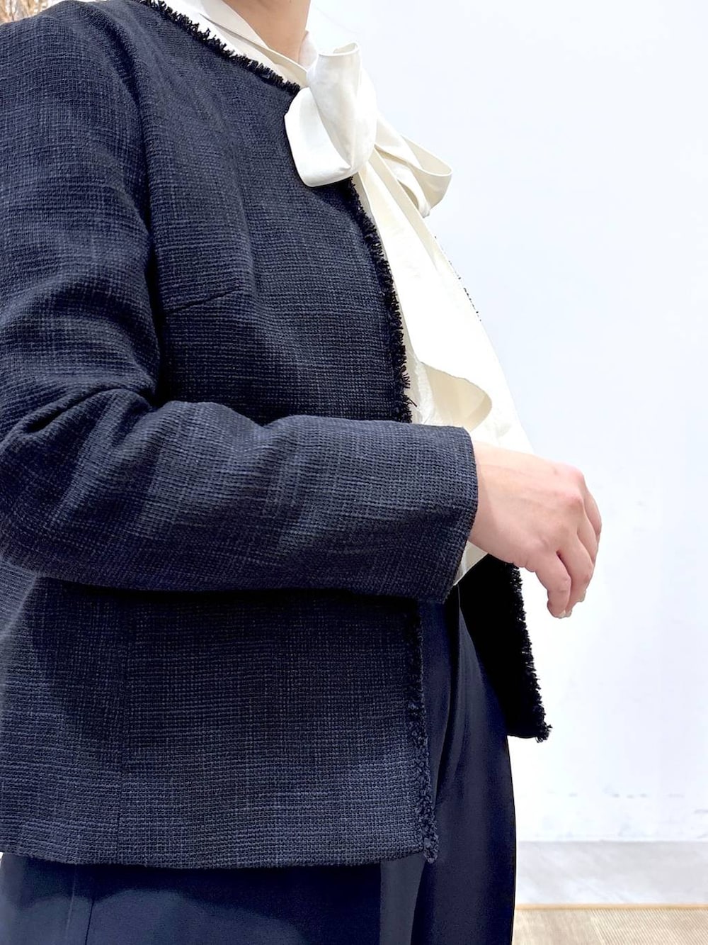 ブラック系のハンドバッグ、ブルー系のノーカラージャケット、ブルー系のスラックスを着用したレディースの冬コーディネートの7枚目の写真