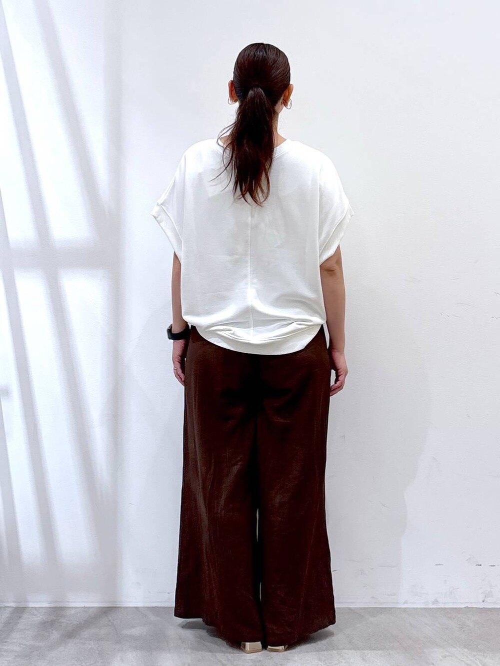 ブラウン系のその他パンツ、ゴールド系のサンダル、ホワイト系のTシャツ/カットソーを着用したレディースの夏コーディネートの3枚目の写真