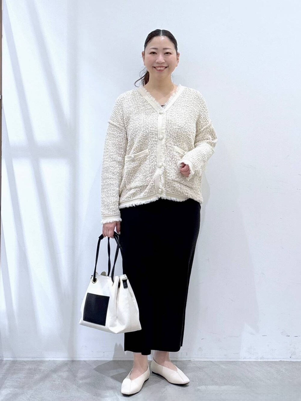 ベージュ系のスカート、ホワイト系のパンプス、ホワイト系のトートバッグを着用したレディースの冬コーディネートの2枚目の写真