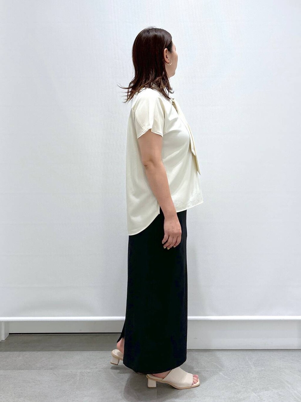 ホワイト系のシャツ/ブラウス、ホワイト系のサンダル、ブラック系のスカートを着用したレディースの夏コーディネートの5枚目の写真