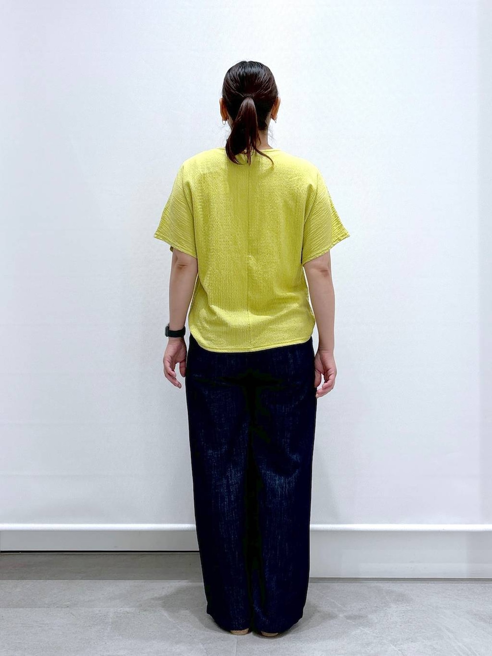 ブルー系のデニムパンツ、ベージュ系のサンダル、イエロー系のTシャツ/カットソーを着用したレディースの夏コーディネートの4枚目の写真