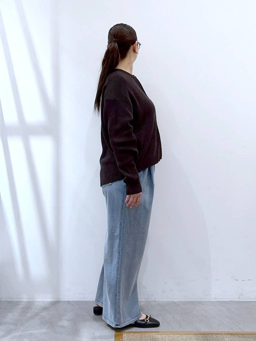 ホワイト系のタンクトップ、ブルー系のデニムパンツ、ブラック系のパンプスを着用したレディースの春コーディネートの5枚目の写真