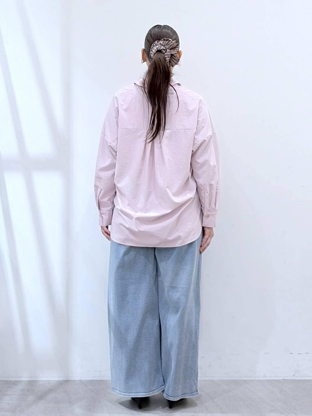 ブルー系のデニムパンツ、ピンク系のシャツ/ブラウス、ベージュ系のショルダーバッグを着用したレディースの春コーディネートの4枚目の写真