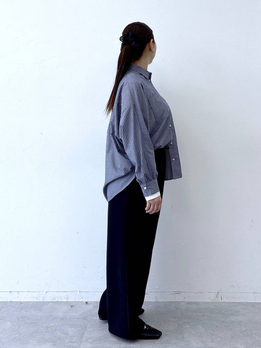 ブラック系のハンドバッグ、ブラック系のパンプス、ブルー系のシャツ/ブラウスを着用したレディースの冬コーディネートの5枚目の写真