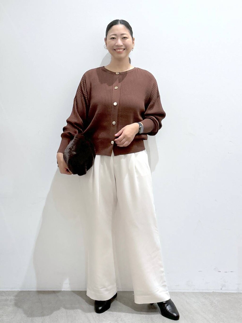 ブラウン系のカーディガン/ボレロ、ブラック系のブーツ、ブラウン系のハンドバッグを着用したレディースの秋コーディネートの2枚目の写真