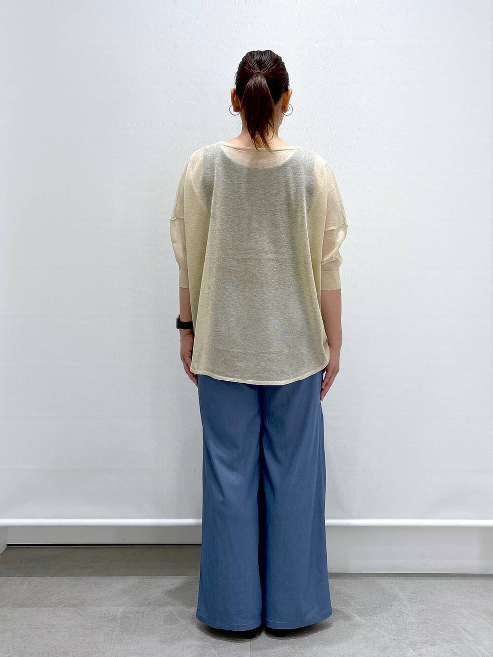 ブルー系のデニムパンツ、ベージュ系のニット/セーター、ブルー系のデニムパンツを着用したレディースの夏コーディネートの3枚目の写真